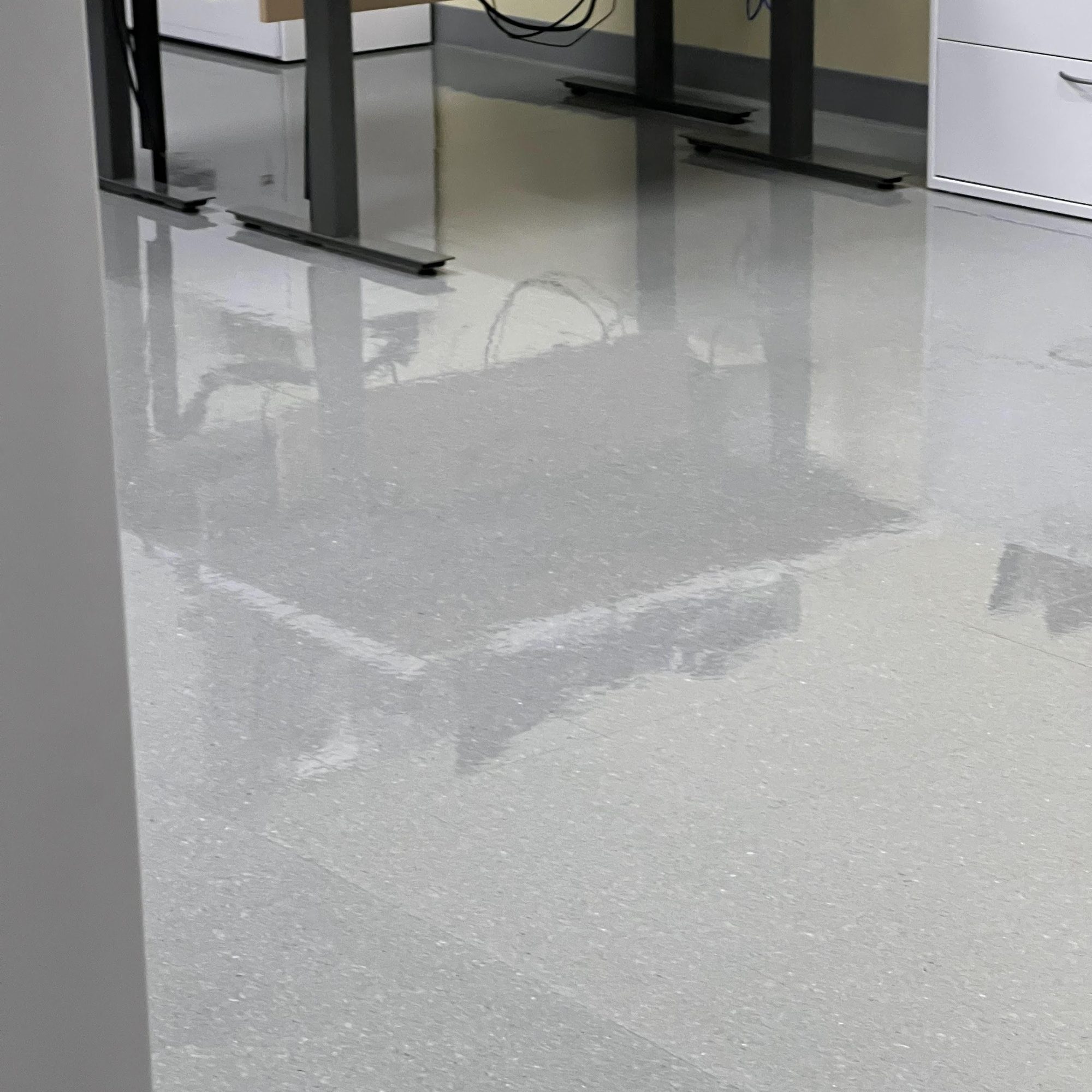 Freshly finished vinyl tile floor under office desks, reflecting the furniture