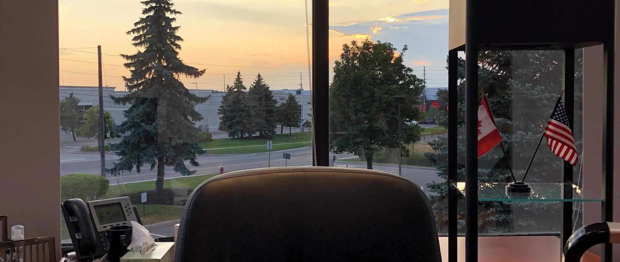 Office windows at dusk looking out over an industrial park
