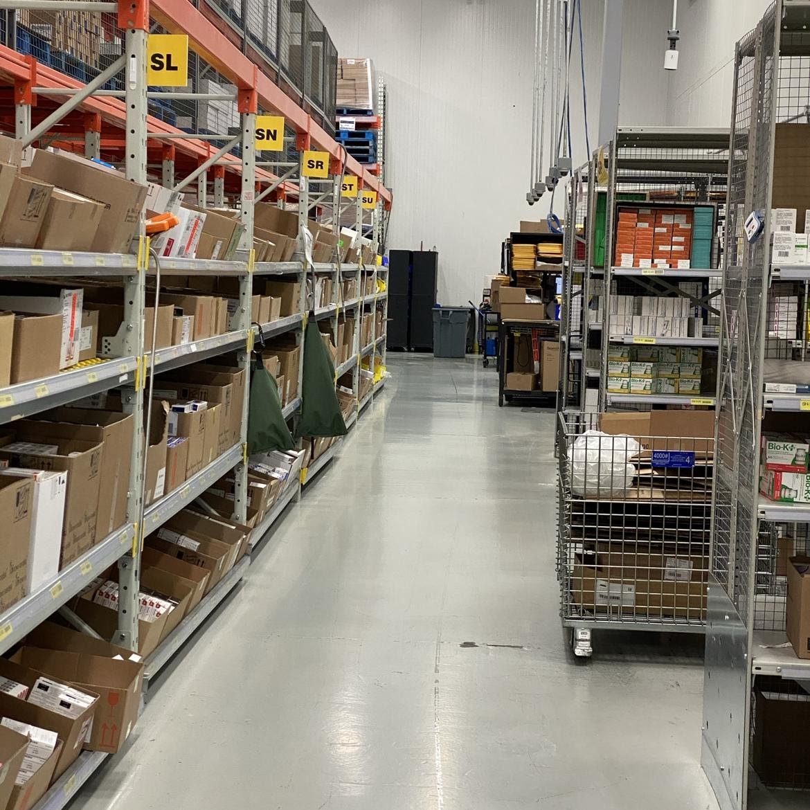 A clean warehouse aisle between stocked shelving, floor freshly scrubbed